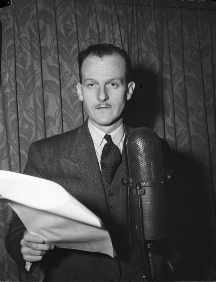 La photo en noir et blanc monter un homme vêtu d'un complet foncé et d'une chemise blanche à rayure qui se tient devant un rideau à motifs. Il est derrière un micro, un paquet de feuilles brochées dans la main droite dont il lit le texte pour la radio. Son regard est levé de ses feuilles, légèrement à gauche de la personne qui le photographie. 